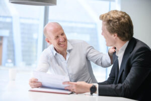 two colleagues smiling with one person patting the others shoulder in a London office.